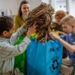 Children with teacher separating rubish in to three bins.