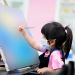 Student baby learn art and paint in watercolor in class. Girls wear mask while in class.